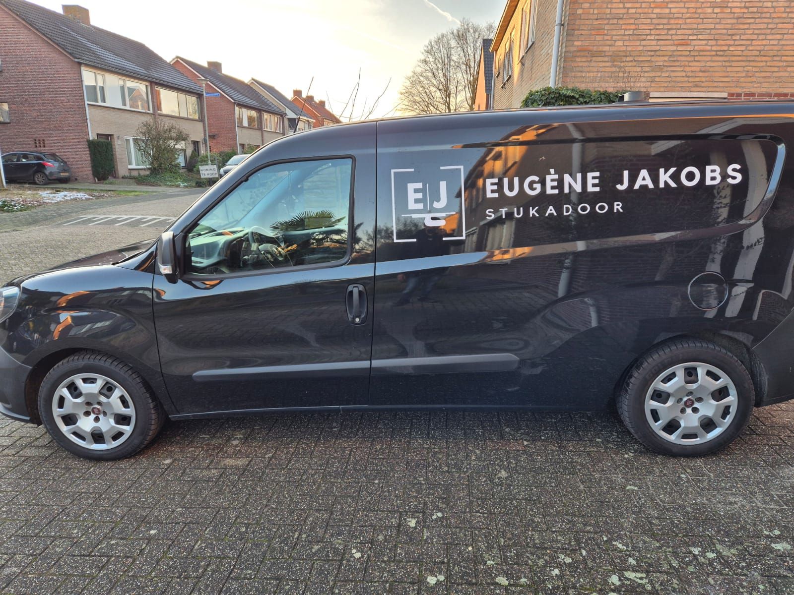 Het zwarte busje van Eugène Jakobs met het witte logo EJ Stukadoor op de zijkant